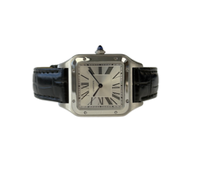 Cartier Santos Dumont Large WSSA0022 (2023) i stål på sort læderrem. Uret måler 31.4 x 43.5 mm og er udstyret med et kvartsværk. Fremstår i nær ny stand uden brugsspor, 9.9/10. Kommer som fuldt sæt med bokse og certifikat. Uret er omfattet af cartier garanti til 2031.