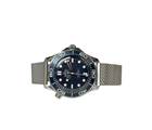 Omega Seamaster Diver 300M James Bond 60th Anniversary 210.30.42.20.03.002 (2026) i stål med blå oxideret aluminiumsurskive med lasergraverede bølger. Uret måler 42 mm og er udstyret med en flot mesh-lænke. Uret fremstår i mint stand uden brugsspor og er delvist i fabriksfolie, 10/10. 
Kommer som fuldt sæt: Bokse, certifikater, manual mv. 
Uret er solgt fra forhandler i Cannes i marts 2026.