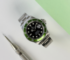Rolex Submariner 16610LV "Kermit" MK1 Flat 4 F-serie (2004) i stål på Oysterlænke med flot grøn aluminiumskrans. Uret fremstår i god stand med mindre brugsspor, 8.5/10. Kommer med boks, yderboks, papirer og servicebevis. 